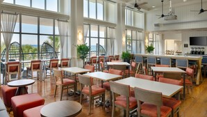 A spacious dining area with high ceilings, large windows, and a view of the ocean.