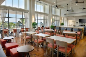 A spacious dining area with high ceilings, large windows, and a view of the ocean.
