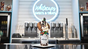 A dessert with a cookie and chocolate chips, a jar labeled 'Whitecaps Sweets & Treats,' and a neon sign in the background. - Hampton Inn & Suites Myrtle Beach/Oceanfront (Myrtle Beach)