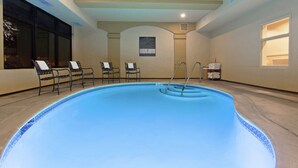 An indoor swimming pool with a tiled edge, benches around the perimeter, and a ladder leading into the water. - Hampton Inn Santa Cruz (Santa Cruz)