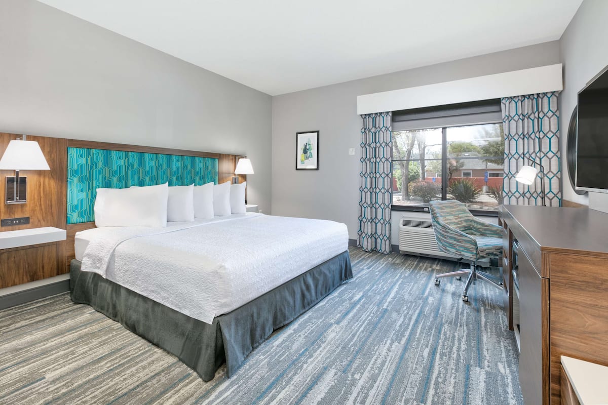 A hotel room with a large bed, a desk, and a TV.