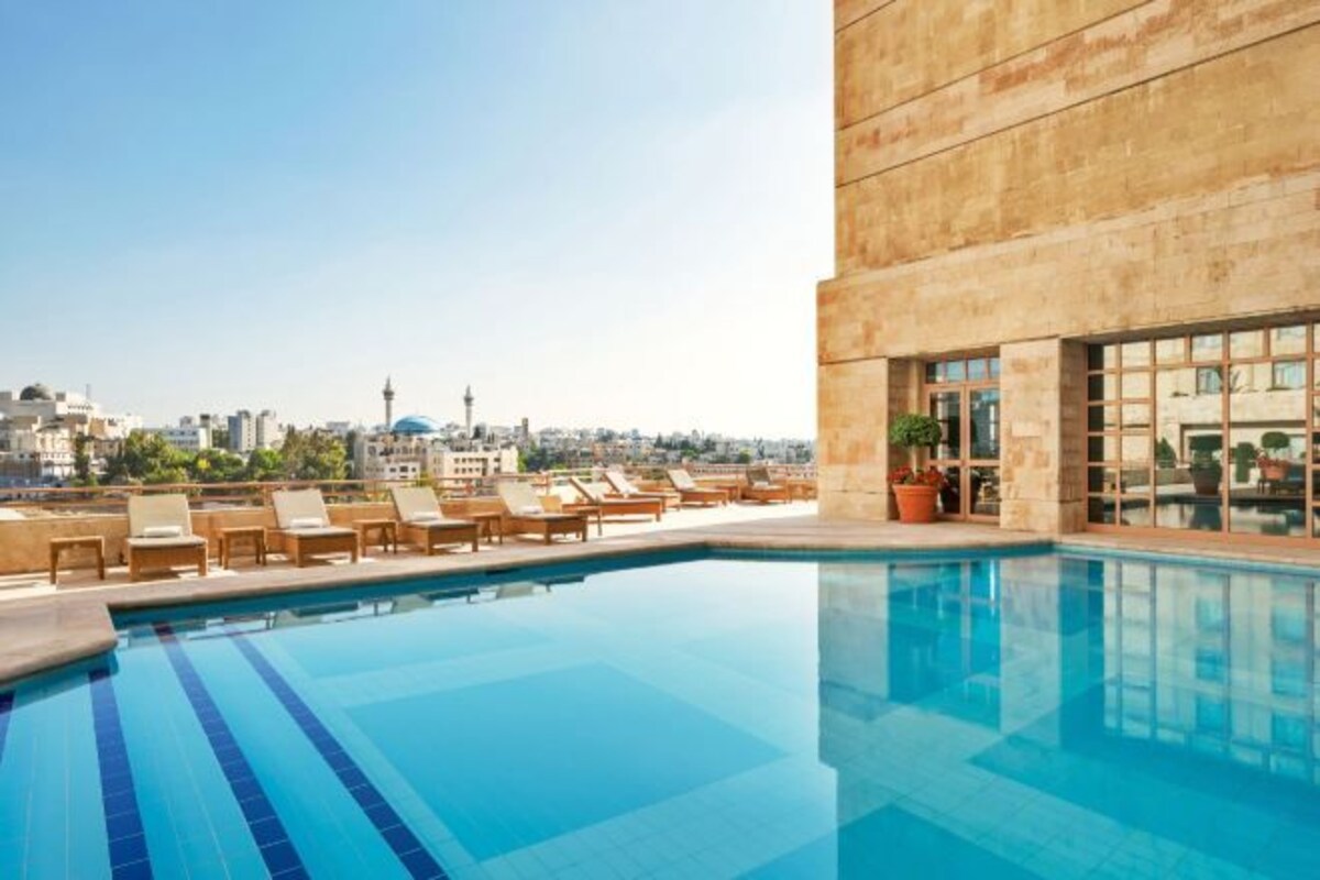 A rooftop pool with lounge chairs and a city view.