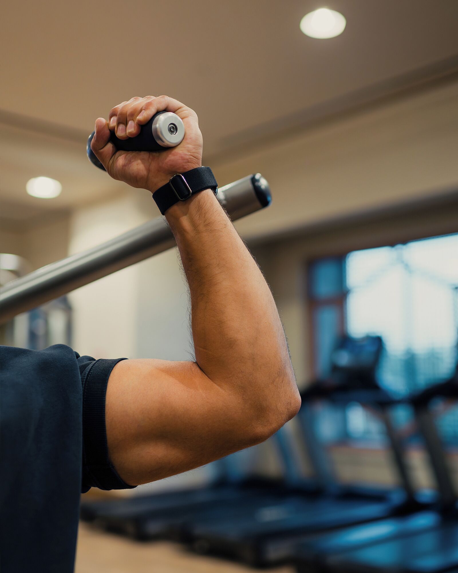 A close-up of a person's arm holding a dumbbell with a weightlifting belt.