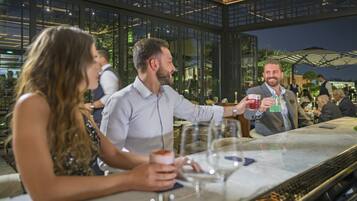 A bar area with tables and chairs, large windows, and a view of the outdoors.