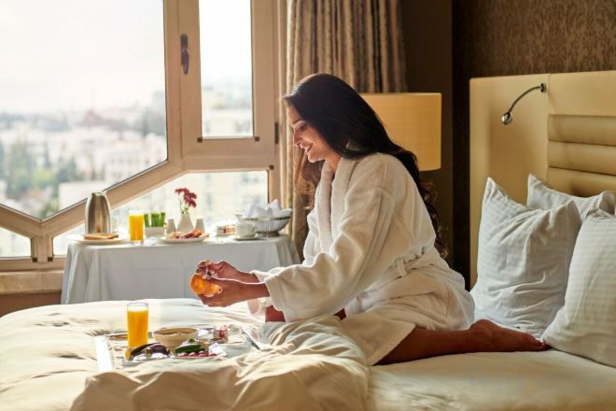 A room with a bed, a window, and a table with breakfast items.