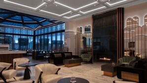 A modern lounge area with seating, a fireplace, and a large window overlooking a cityscape. - Grand Hyatt Amman (Amman)