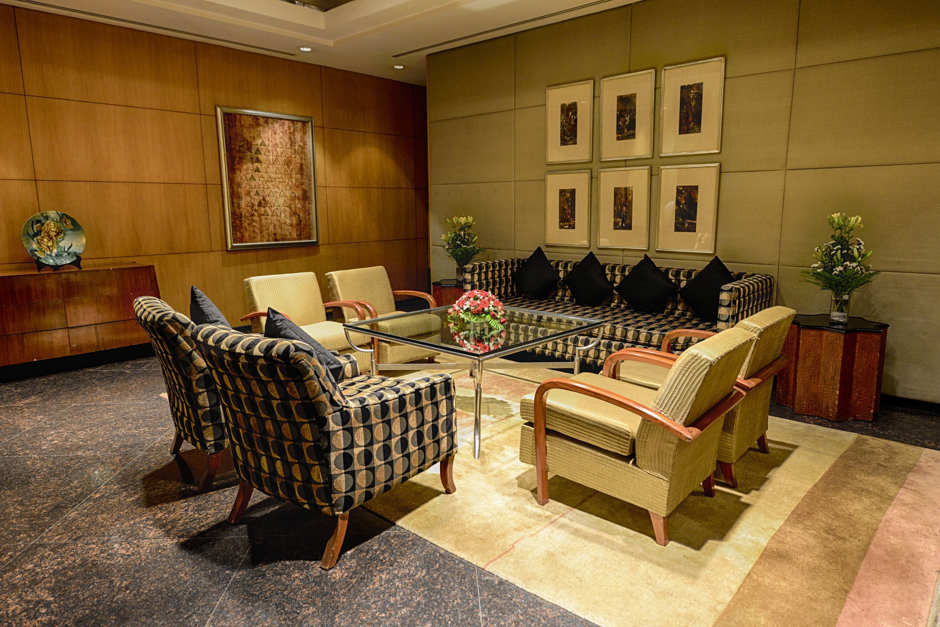 A conference room with a glass table, patterned chairs, and a large painting on the wall.