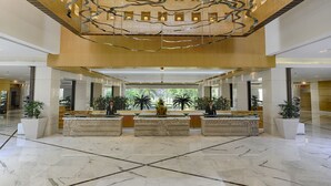 Un'ampia hall con pavimenti in marmo, un banco reception centrale e un moderno design del soffitto.