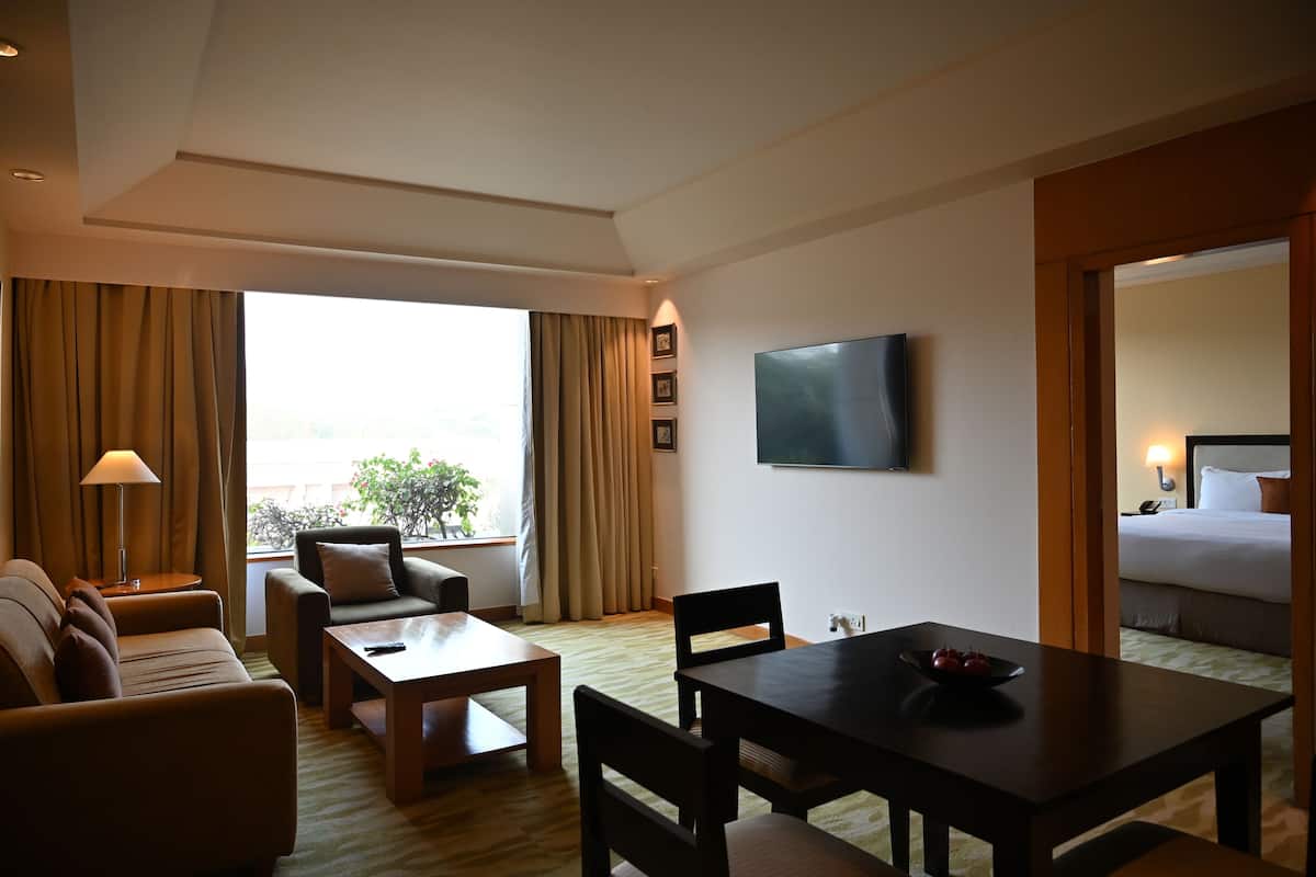A hotel room with a sofa, a dining table, a TV, and a bed.
