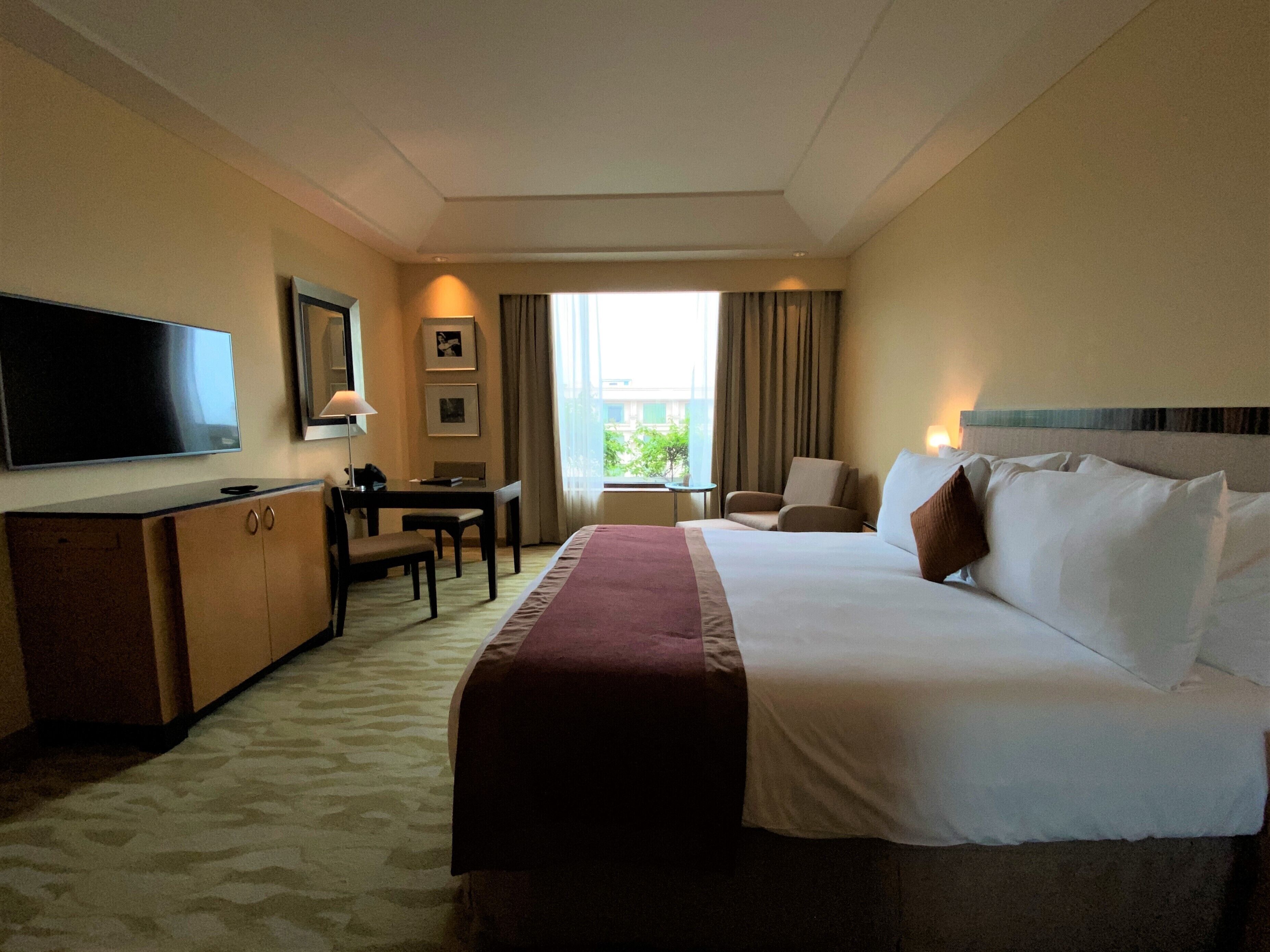 A hotel room with a large bed, a television, a desk, and a chair.