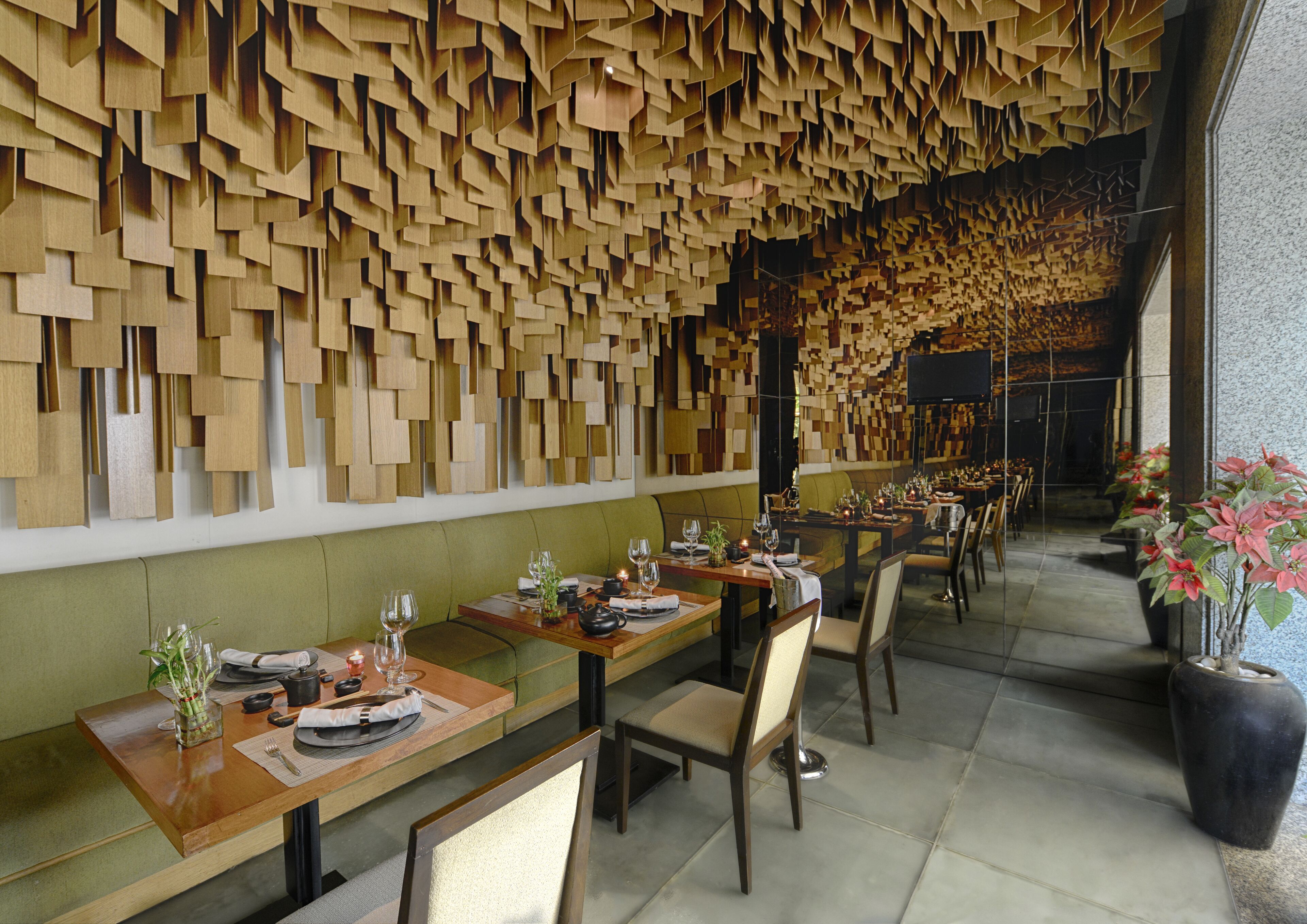 A restaurant with wooden wall decor, green cushioned seating, and a tiled floor.