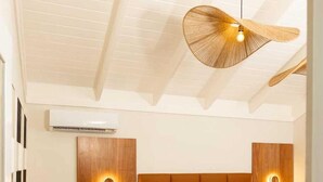 Una habitación de hotel moderna con una cama grande, cabecera de madera, mesitas de noche con lámparas, un escritorio y una silla.
