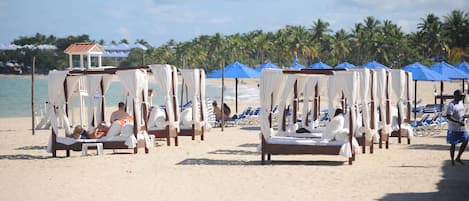 Aan het strand, wit zand, ligstoelen aan het strand, parasols