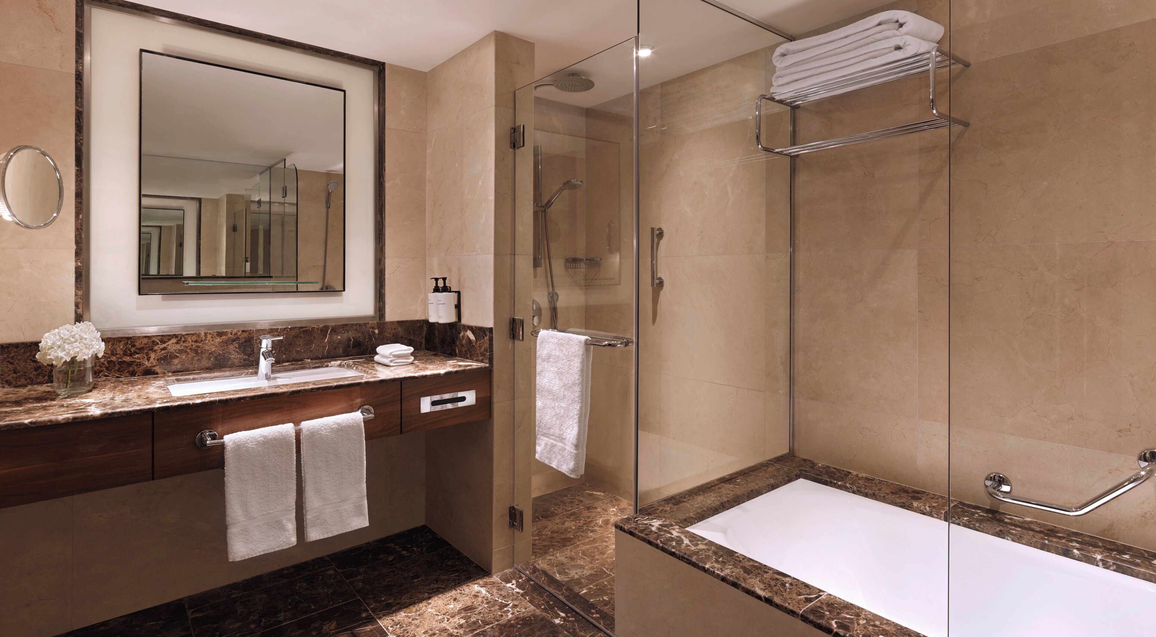 A modern bathroom with a glass-enclosed shower, a marble countertop, and a large mirror.