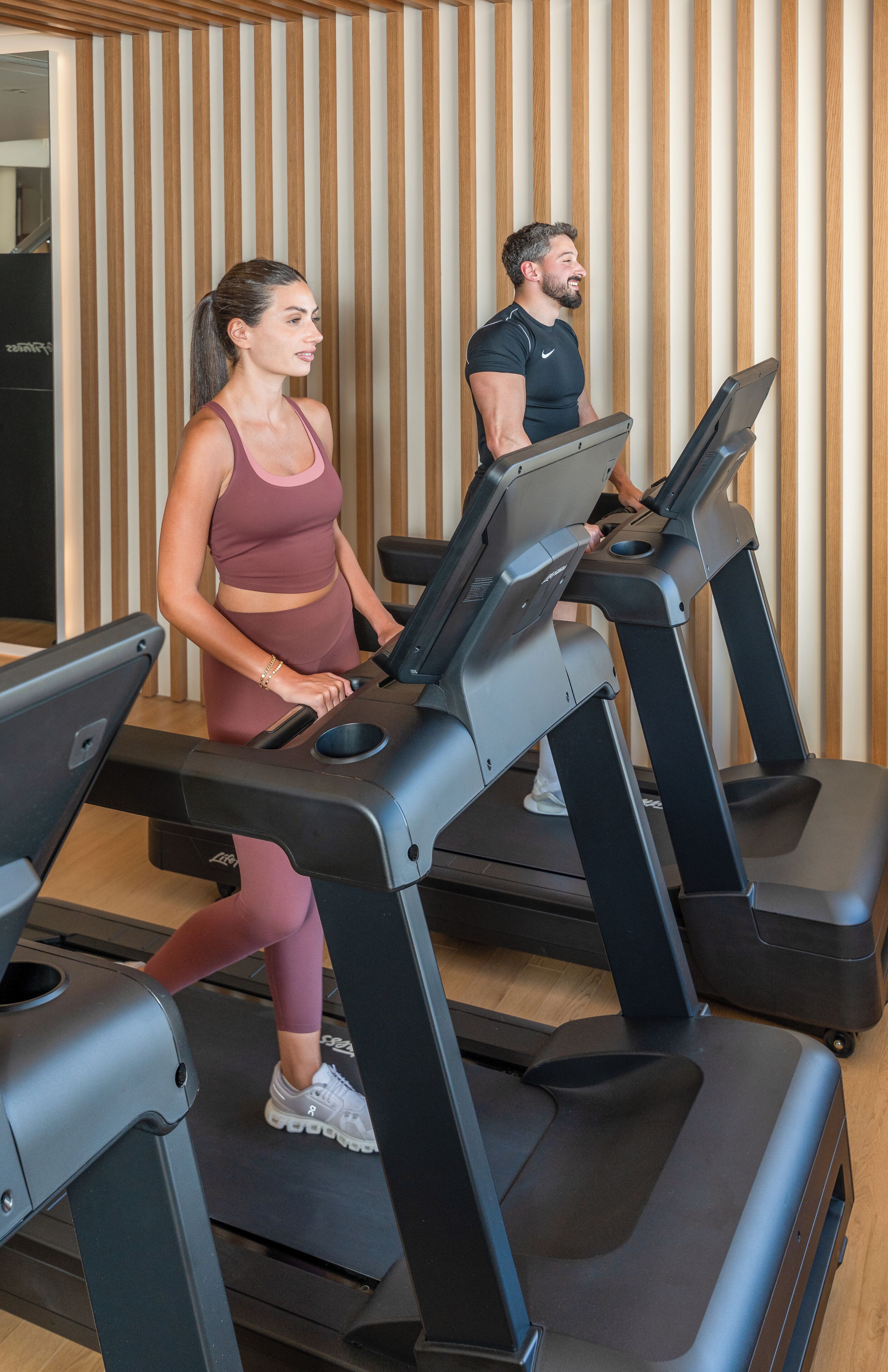 A gym with treadmills and a wooden wall in the background.