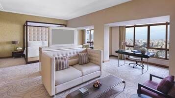 A hotel room with a sofa, a desk, and a view of the city.