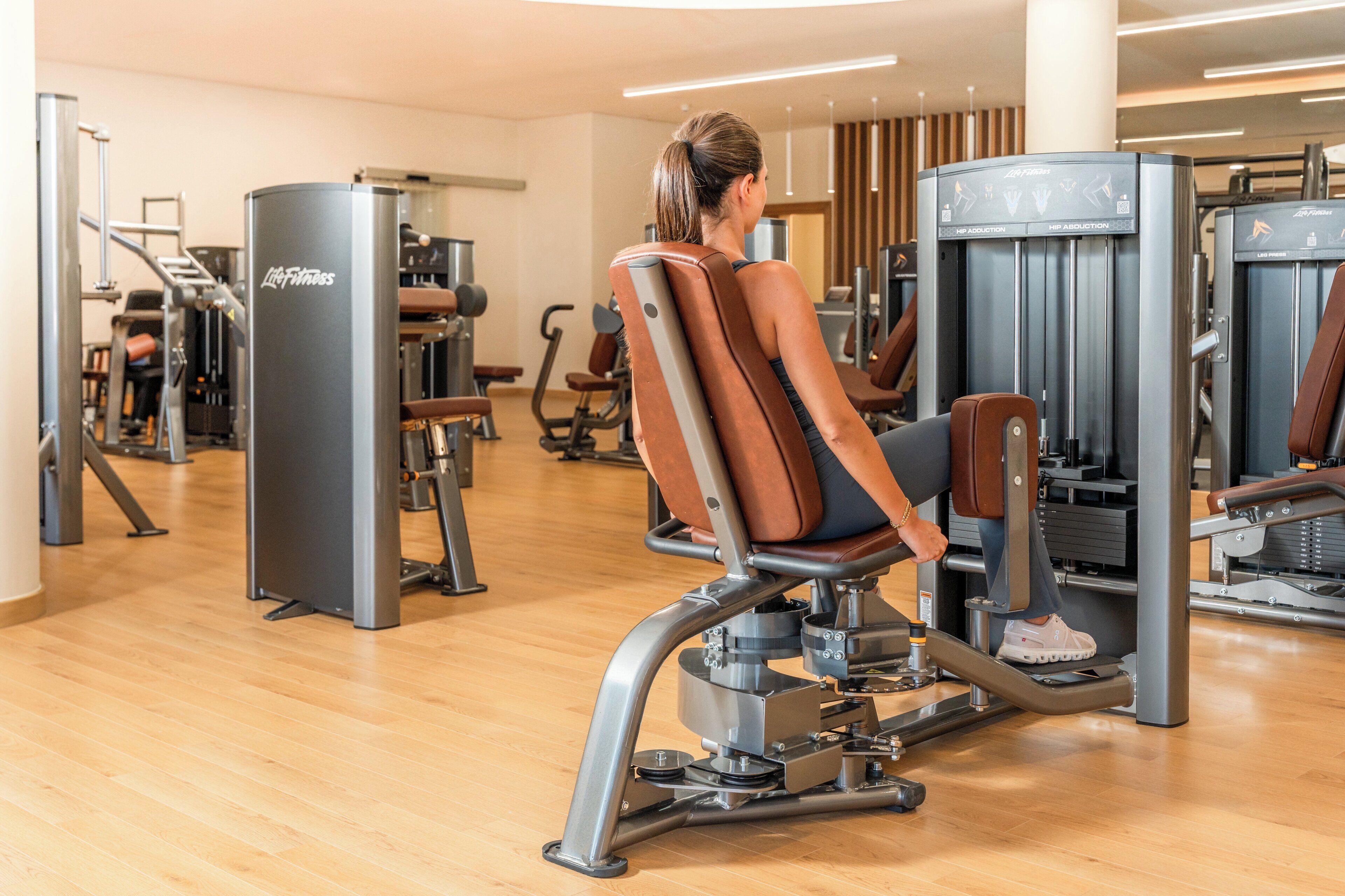 A gym with various exercise machines, including a leg press and a hip abduction machine.