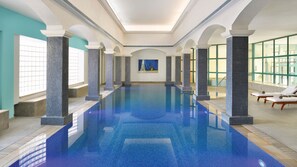 A large indoor swimming pool with tiled walls and columns, sunlit by natural light from large windows. - InterContinental AMMAN JORDAN by IHG (Amman)