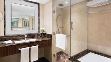 Une salle de bain moderne avec un comptoir en marbre, une douche à l’italienne et un grand miroir.