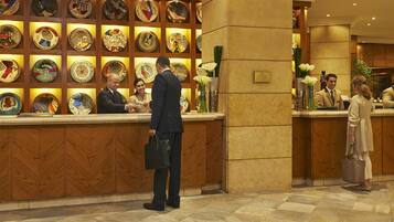 A hotel reception area with a wall of decorative plates and a reception desk.