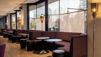 Ein modernes Interieur mit Sitzgelegenheiten, Tischen und großen Fenstern.