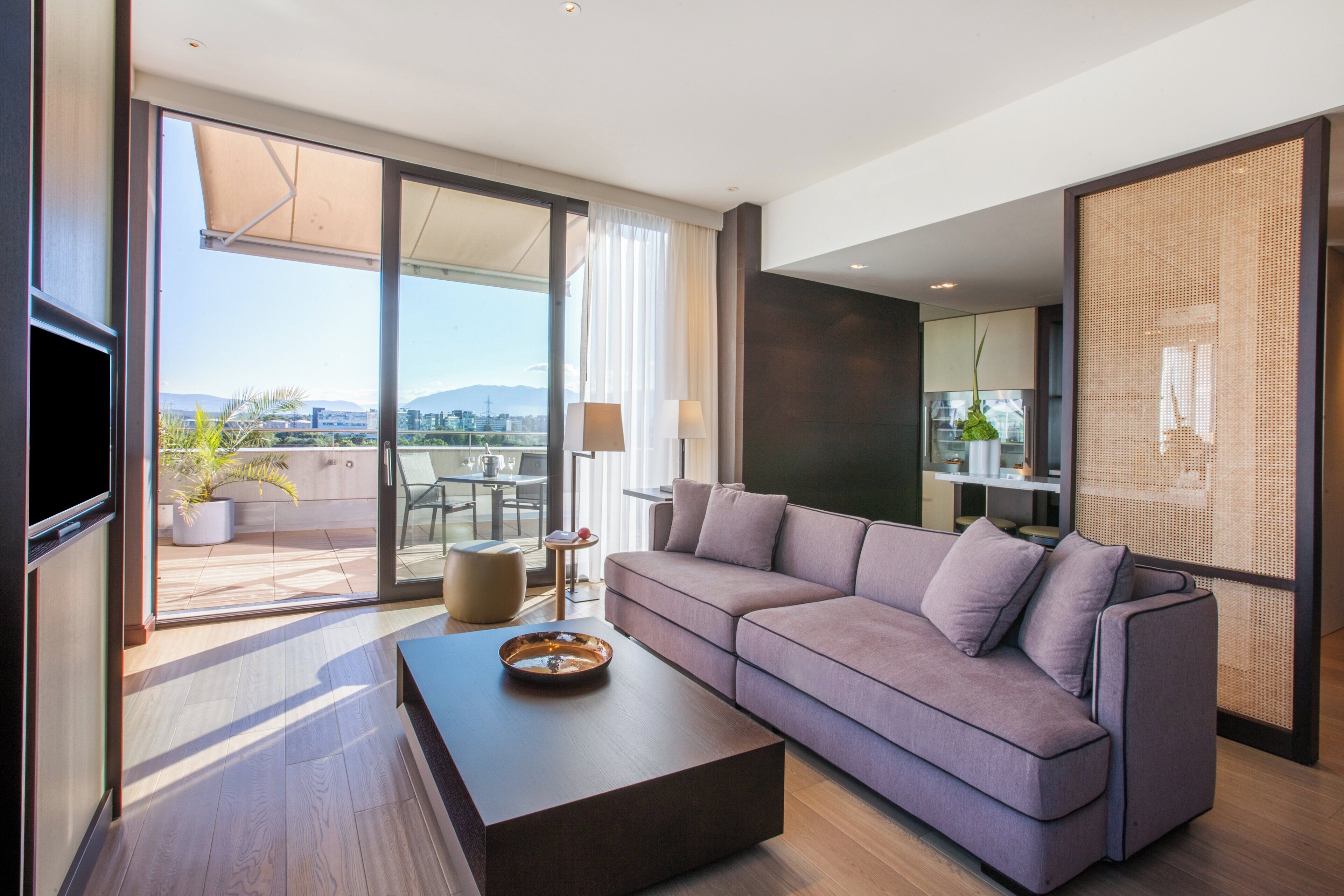 Una sala de estar moderna con un sofá, una mesita de centro y vistas a la ciudad a través de amplios ventanales.