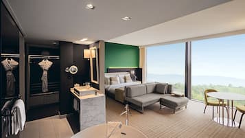Habitación de hotel moderna con una cama grande, un sofá, una mesa de comedor y vistas a la montaña.