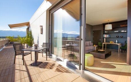 A modern outdoor living area with a patio, seating, and a view of the mountains.