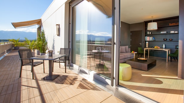 A modern outdoor living area with a patio, seating, and a view of the mountains. - Crowne Plaza Geneva by IHG (Meyrin)