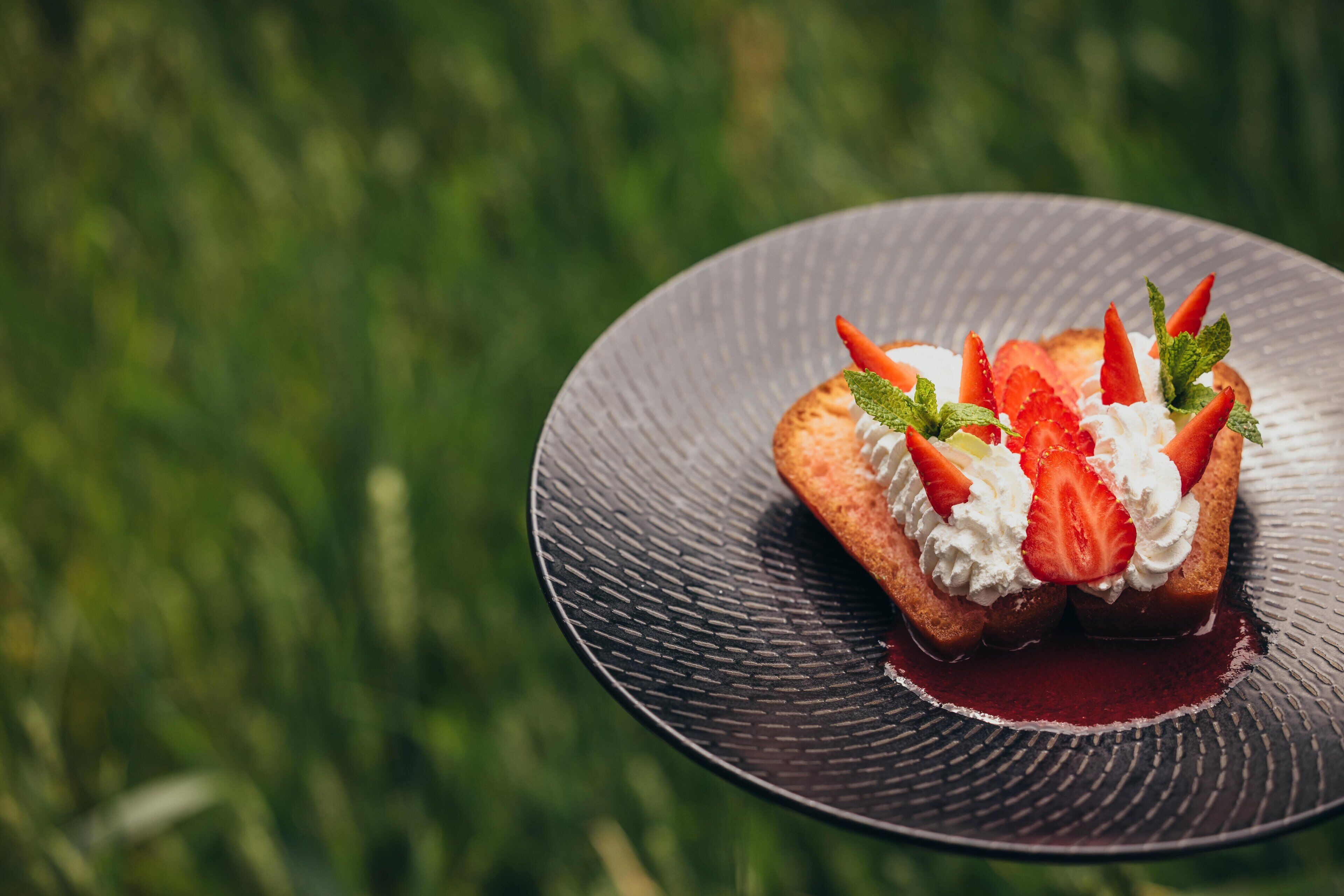 A dessert on a textured plate with a blurred green background.