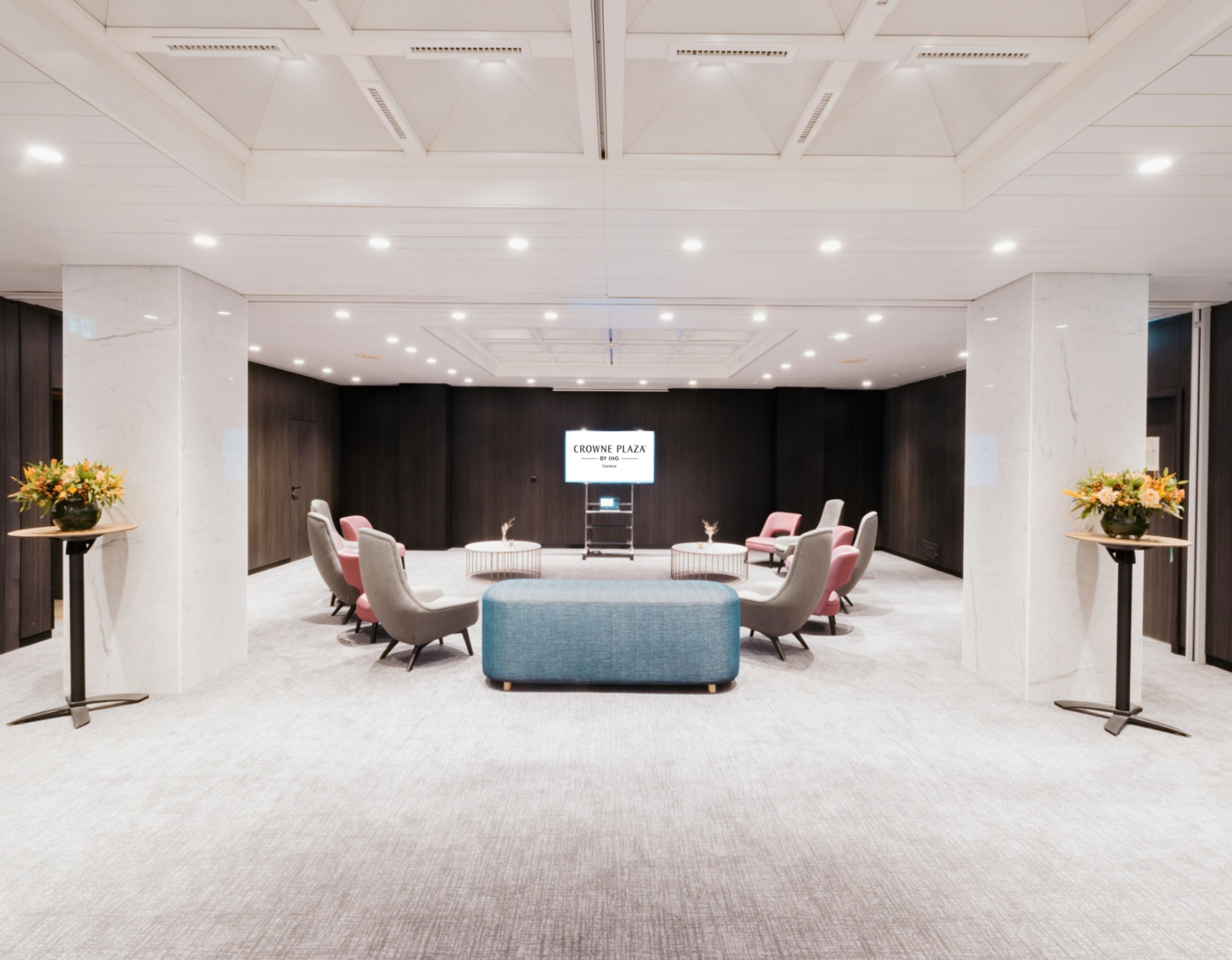 A conference room with a large screen, multiple seating arrangements, and a central table.