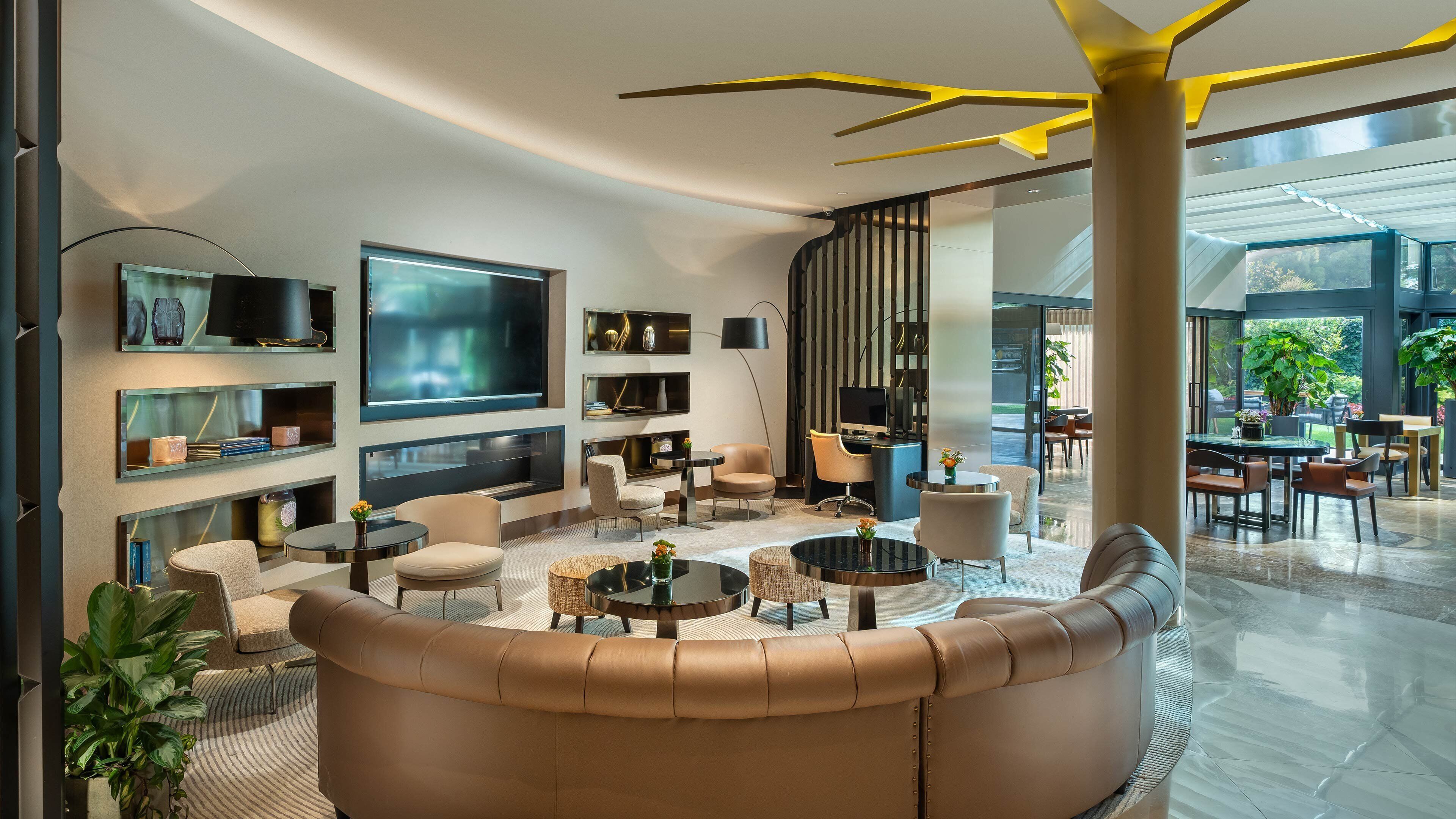 Una sala de estar moderna con televisor grande, asientos cómodos y vistas al exterior.