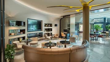 Una sala de estar moderna con televisor grande, asientos cómodos y vistas al exterior.