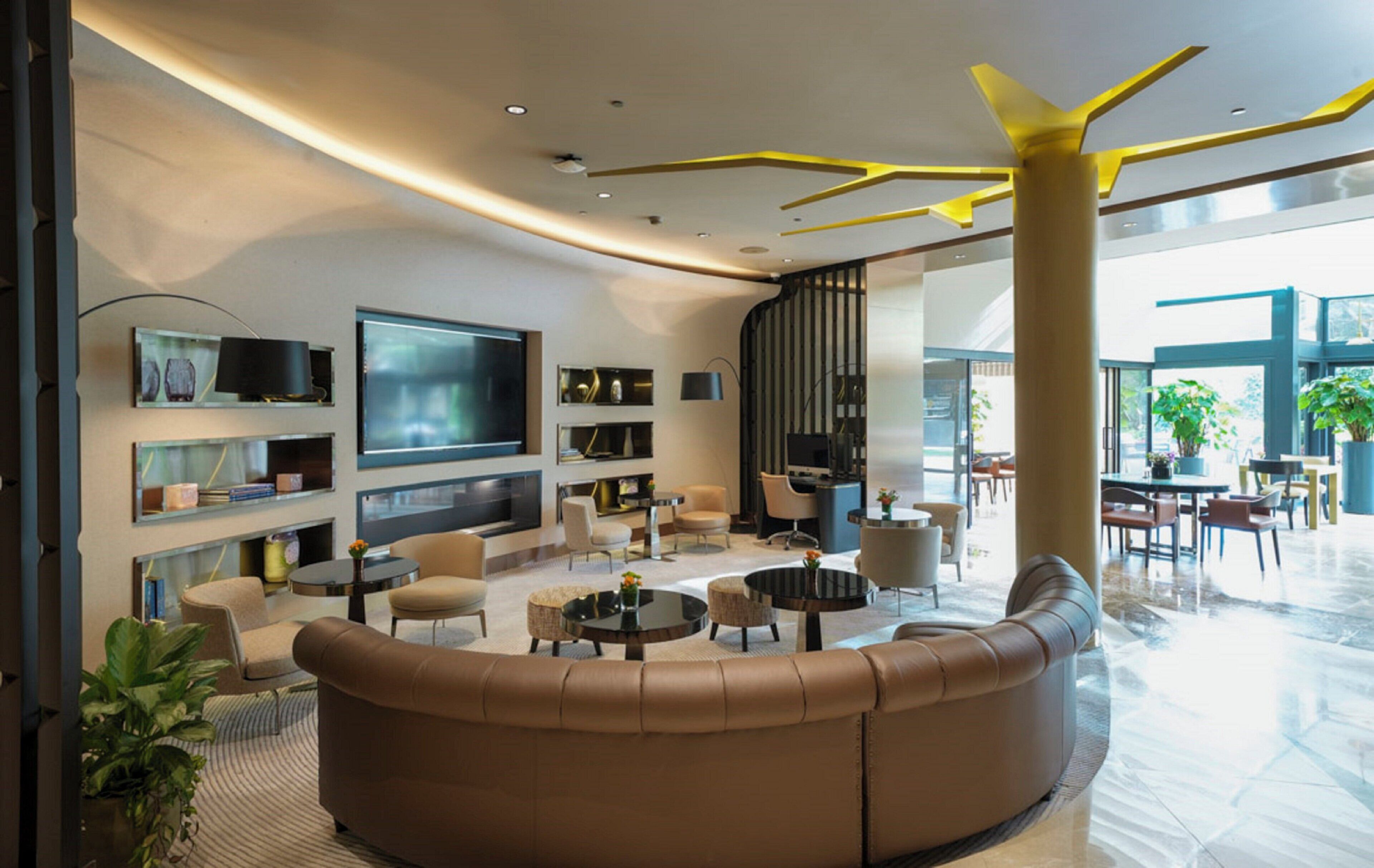 A modern living room with a curved sofa, round coffee tables, and a flat-screen TV.