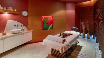 Un spa moderno con un lavamanos grande, una camilla de masaje y una pared de madera con un reloj.