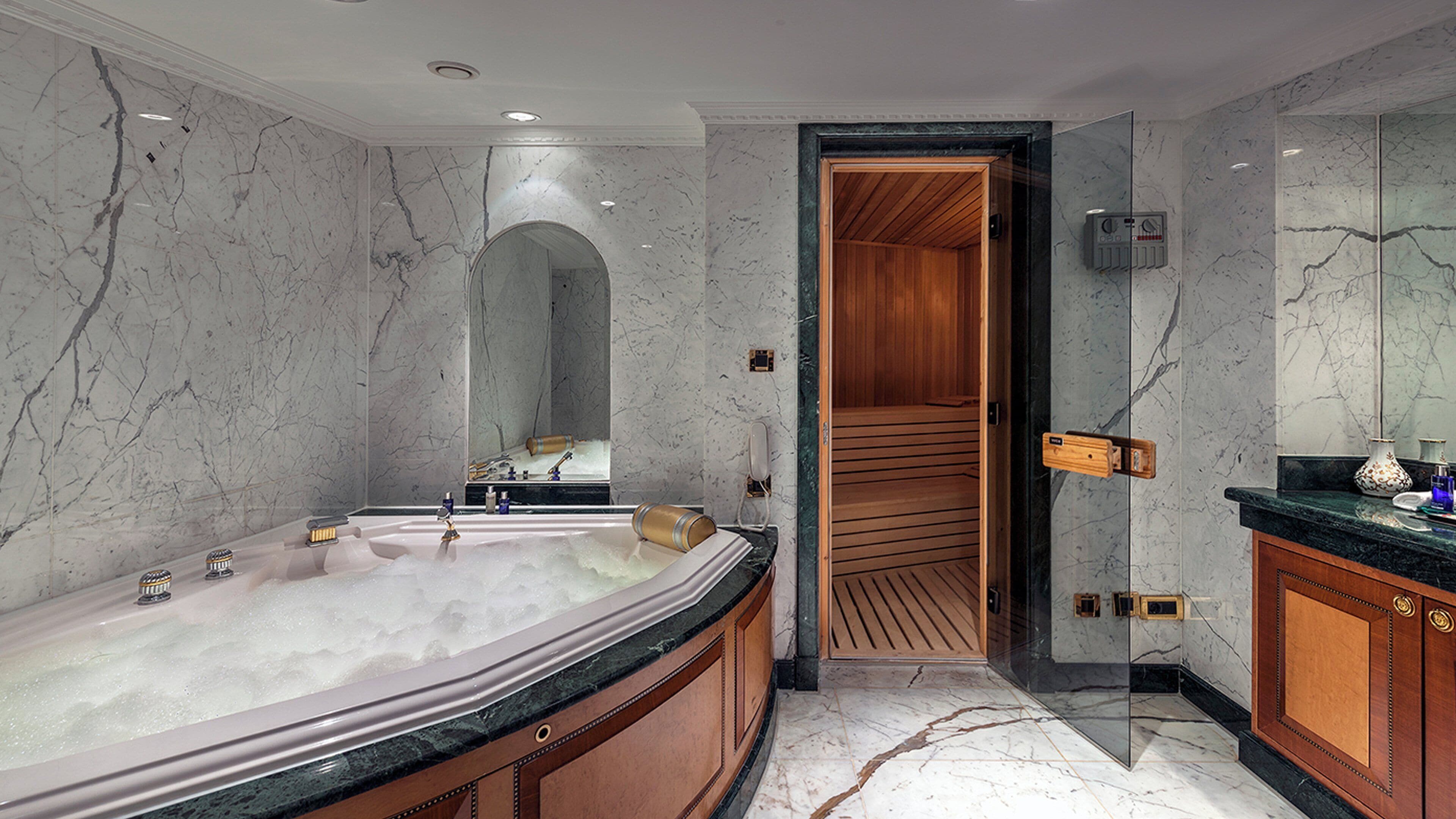 Une salle de bain moderne avec une grande baignoire, un lambris en bois, des murs en marbre et un meuble-lavabo avec un miroir.