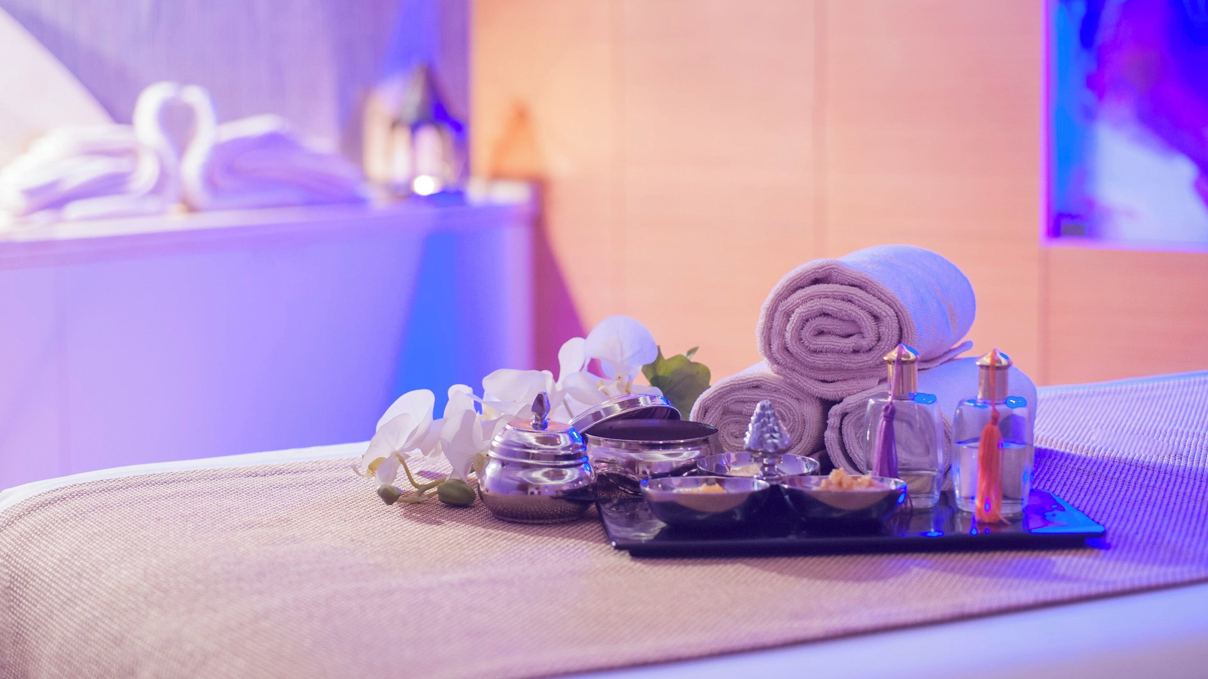 A neatly arranged spa area with towels, a tray of toiletries, and decorative items on a textured surface.