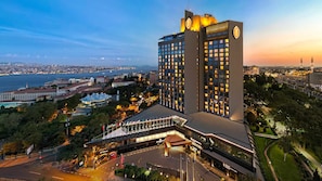 Un hotel moderno con una torre destacada, un vestíbulo amplio y vistas a la ciudad y al agua.