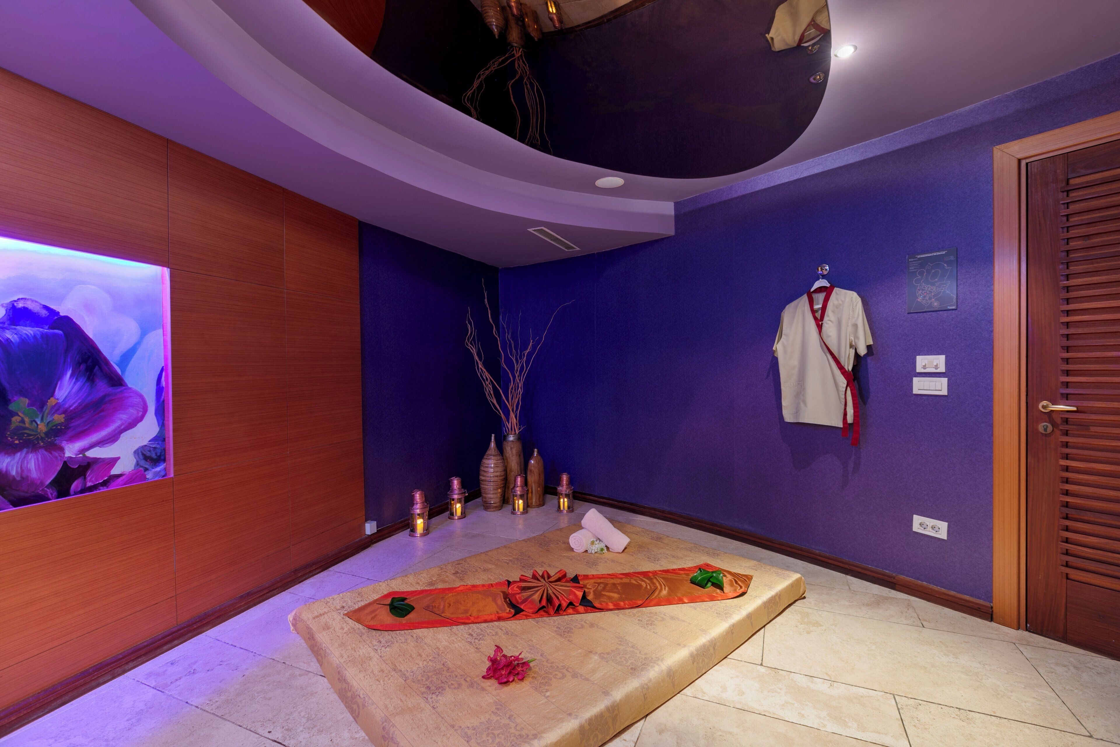 A spa room with a massage table, candles, and a wall-mounted TV.