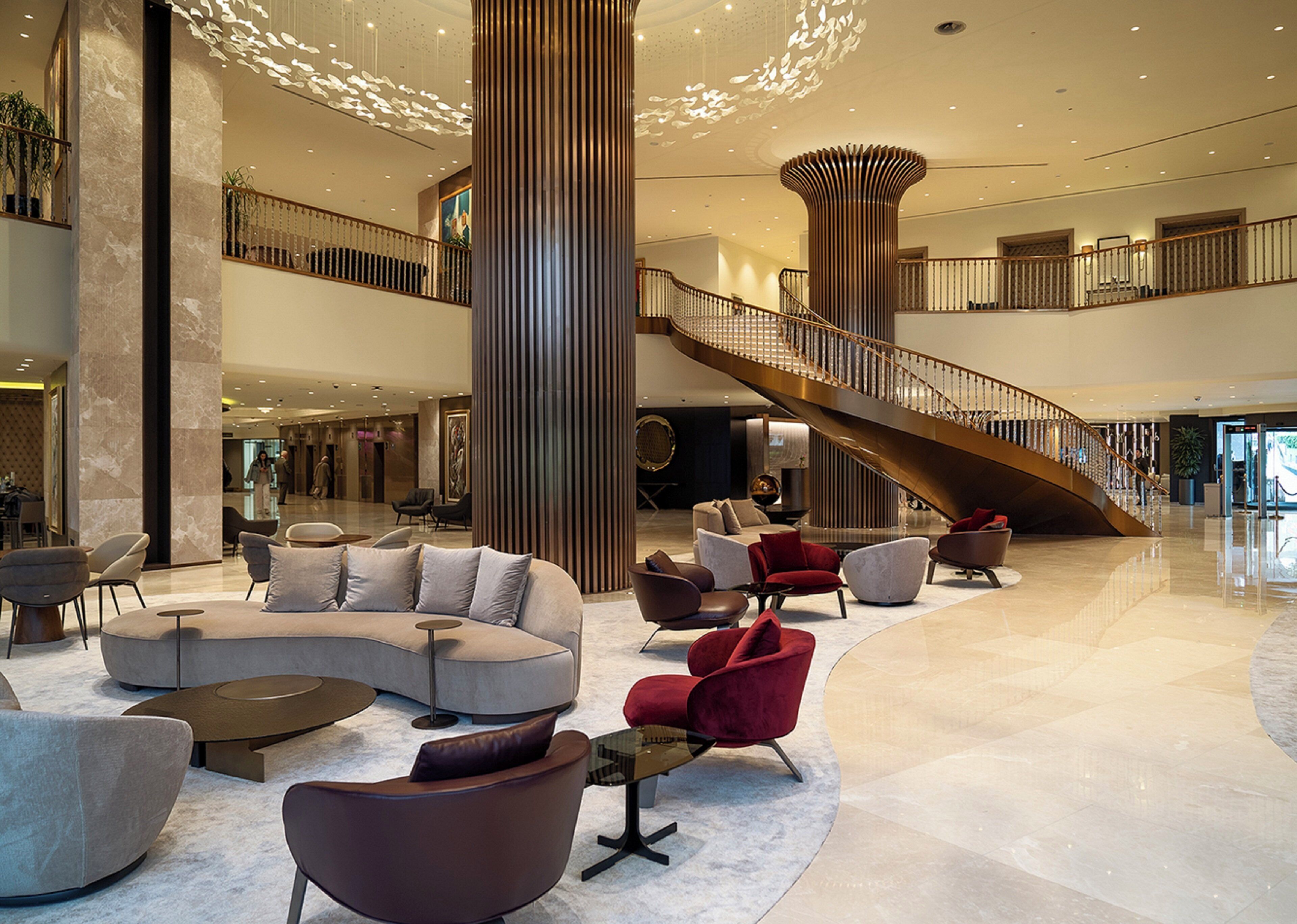 A spacious lobby with a curved seating area, a central column, and a spiral staircase.