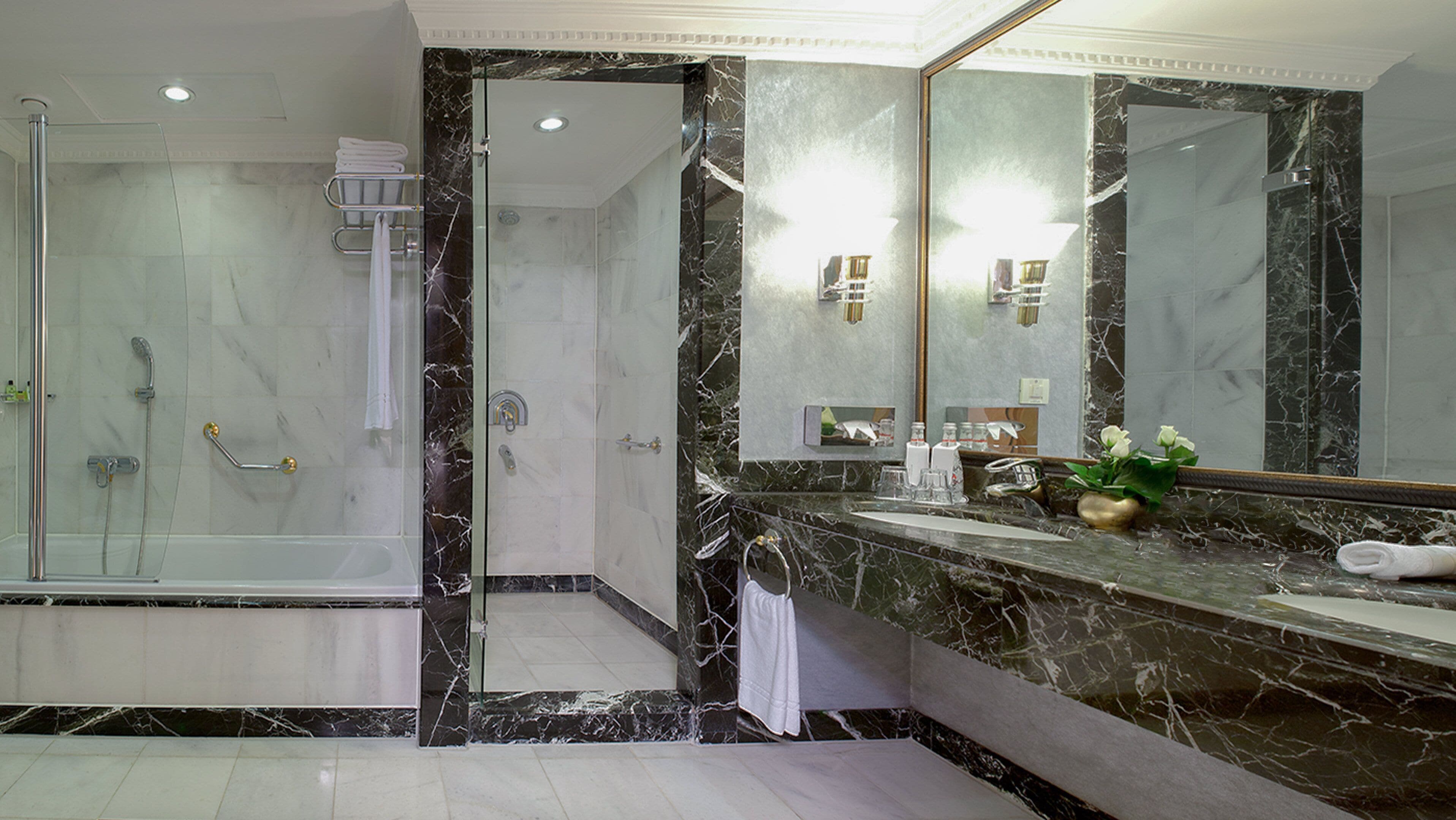 A modern bathroom with a glass-enclosed shower, a marble vanity, and a large mirror.