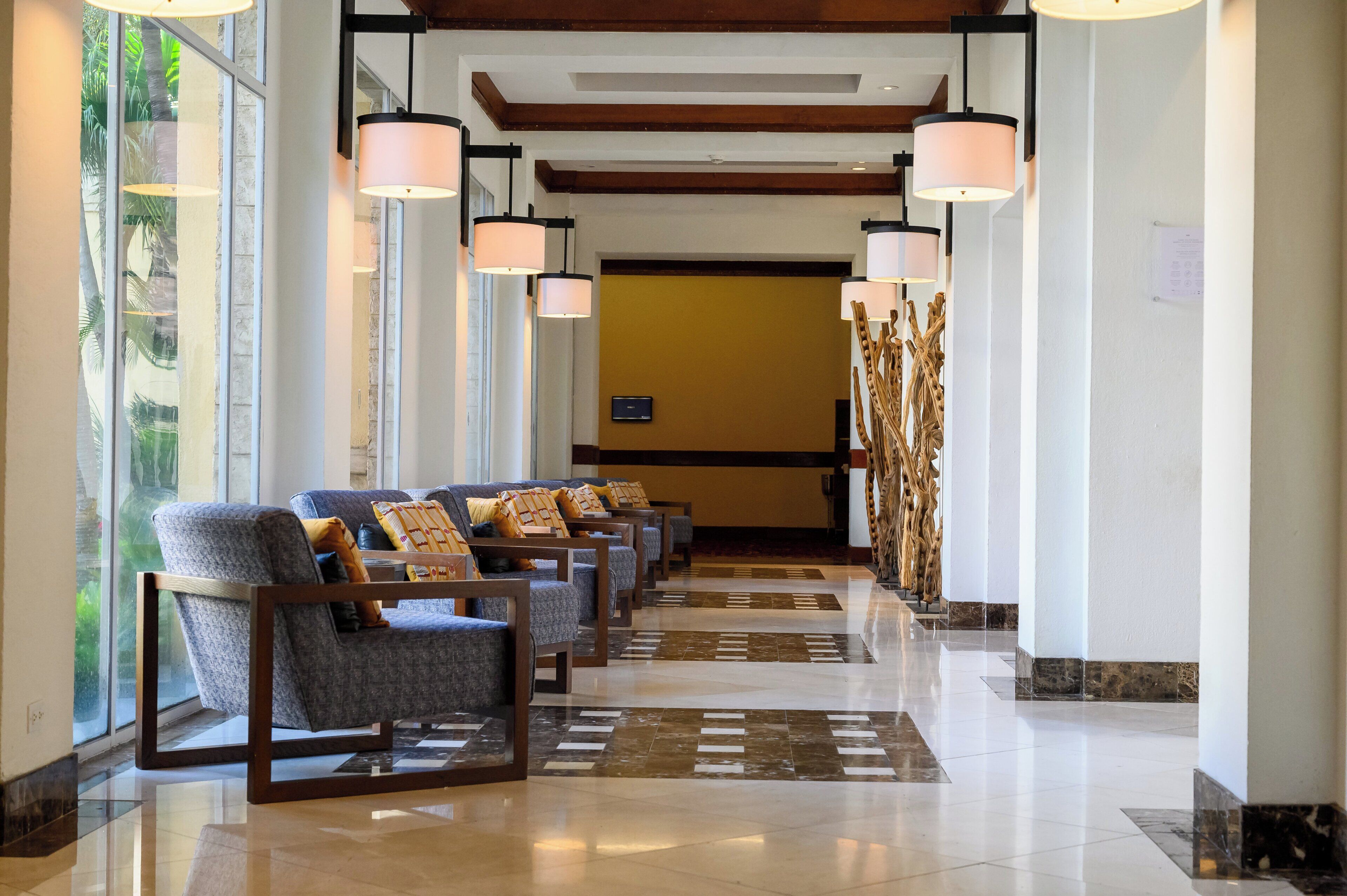 Un hall de hotel con una fila de sillones, una recepción y una pared decorativa.