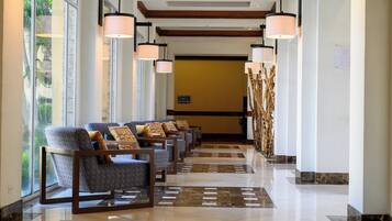 Un hall de hotel con una fila de sillones, una recepción y una pared decorativa.