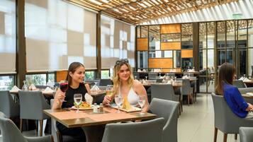 A modern restaurant with wooden ceiling panels, large windows, and a clean, organized layout.