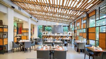 A modern restaurant with a wooden ceiling, large windows, and neatly arranged tables.