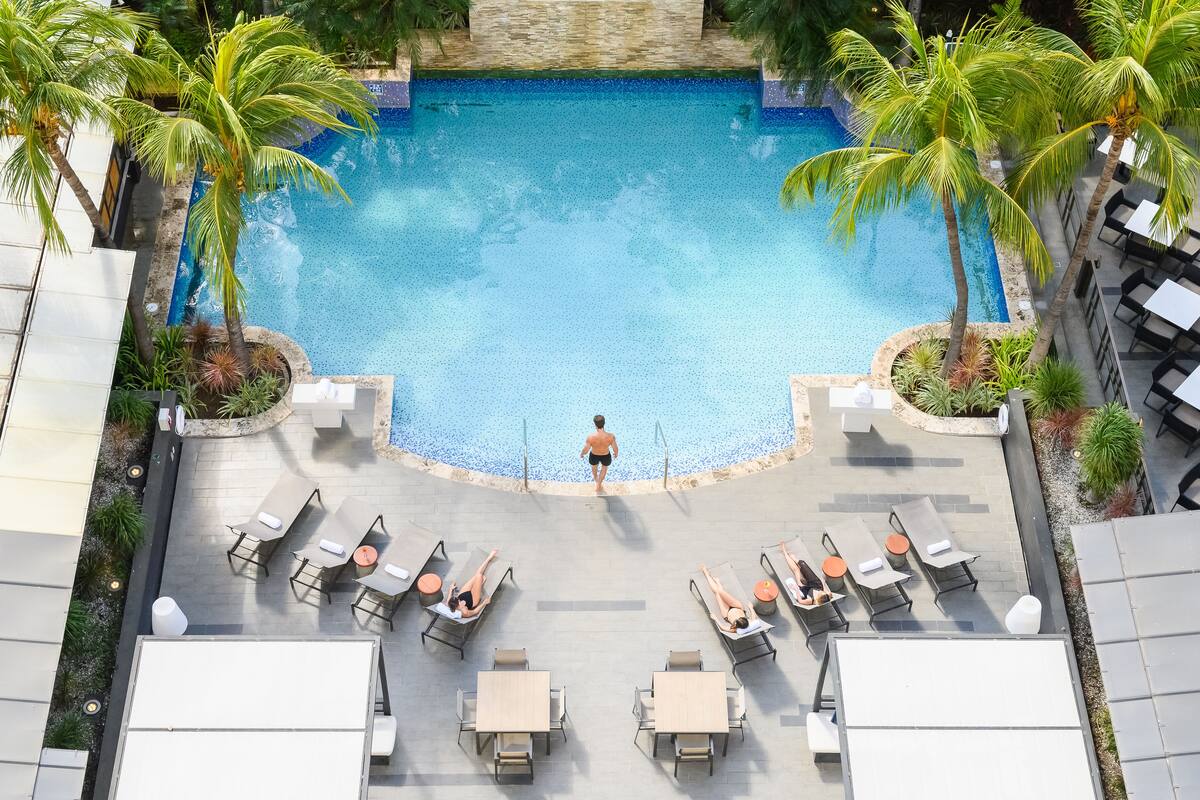 An aerial view of a pool area with lounge chairs and palm trees.