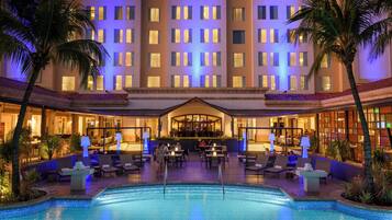 A hotel with a pool, lounge area, and bar.