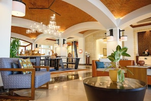 A lobby with a high ceiling, chandeliers, seating areas, and a reception desk. - Real InterContinental Managua at Metrocentro Mall by IHG (Managua)