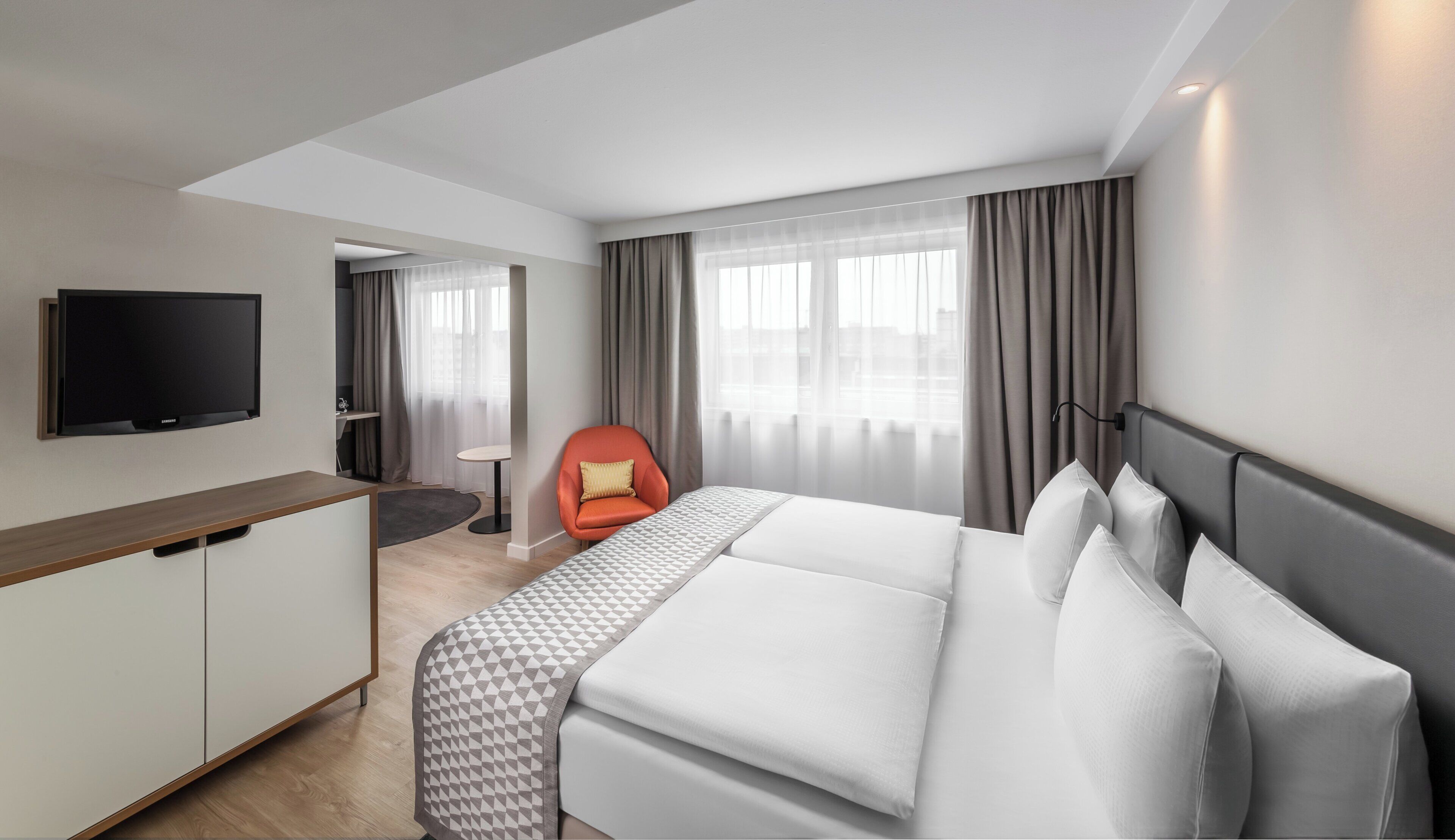 Habitació d'hotel amb llit, televisió, escriptori i cadira.