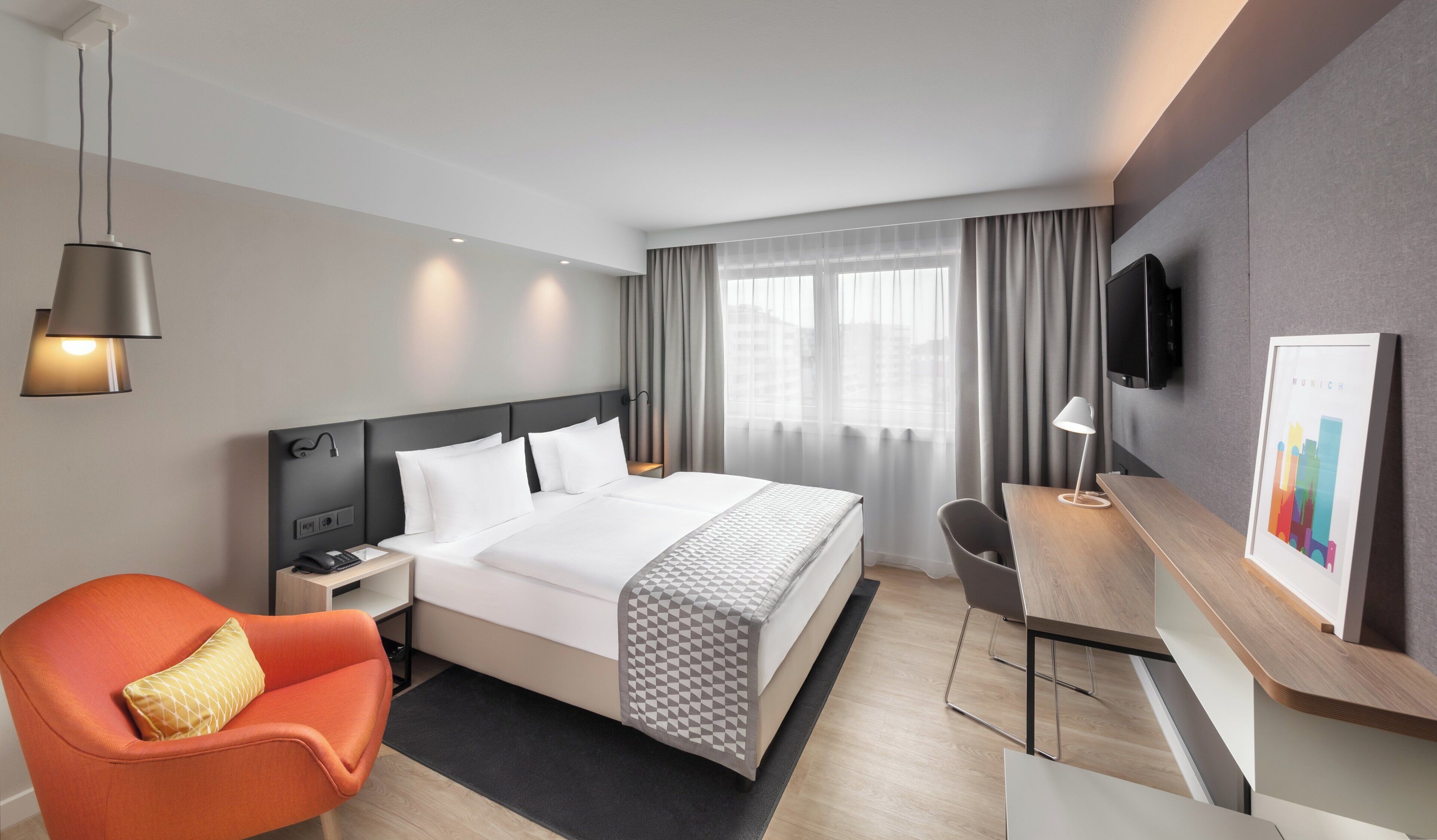 A hotel room with a bed, a desk, a chair, a television, and a window with curtains.
